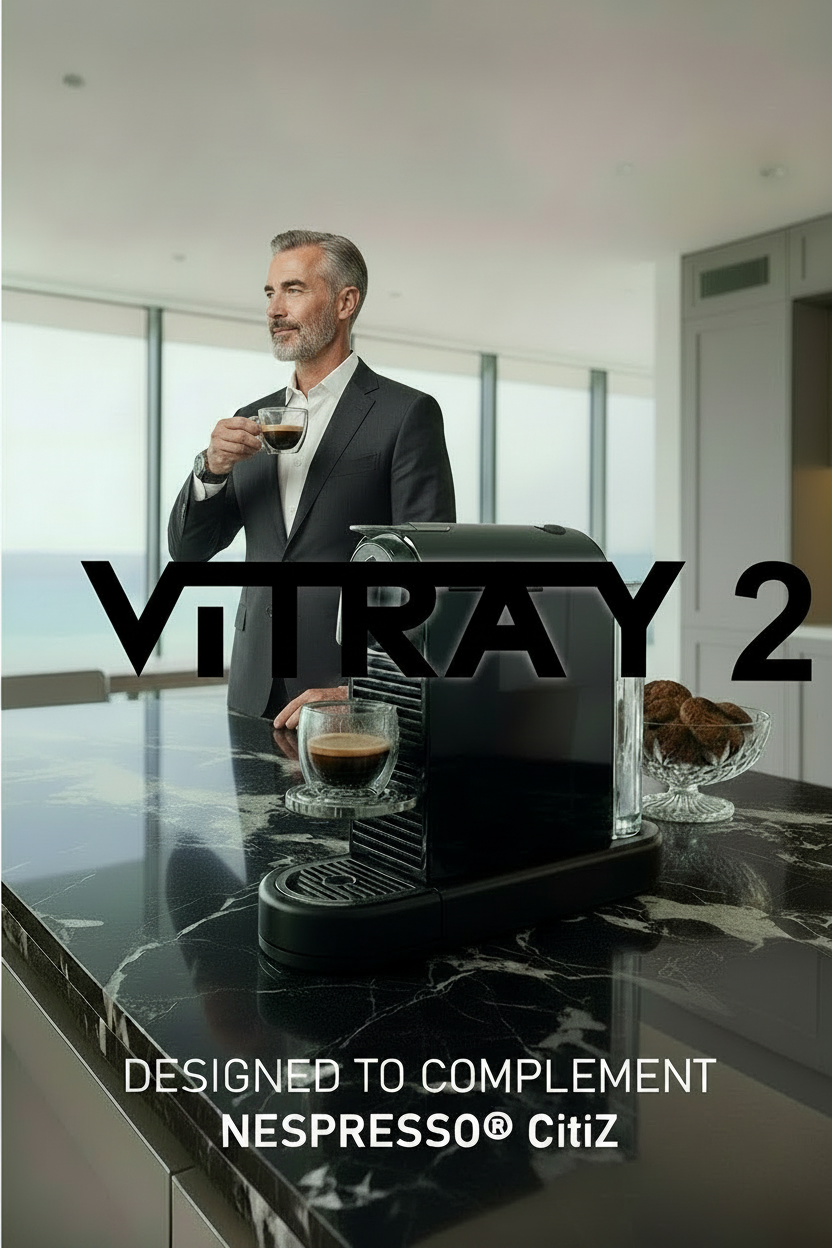 A black Nespresso-style coffee machine sits on a black marble kitchen countertop in a modern bright kitchen. Large overlaid text reads 'ViTRAY 2' and 'DESIGNED TO COMPLEMENT NESPRESSO CitiZ'.